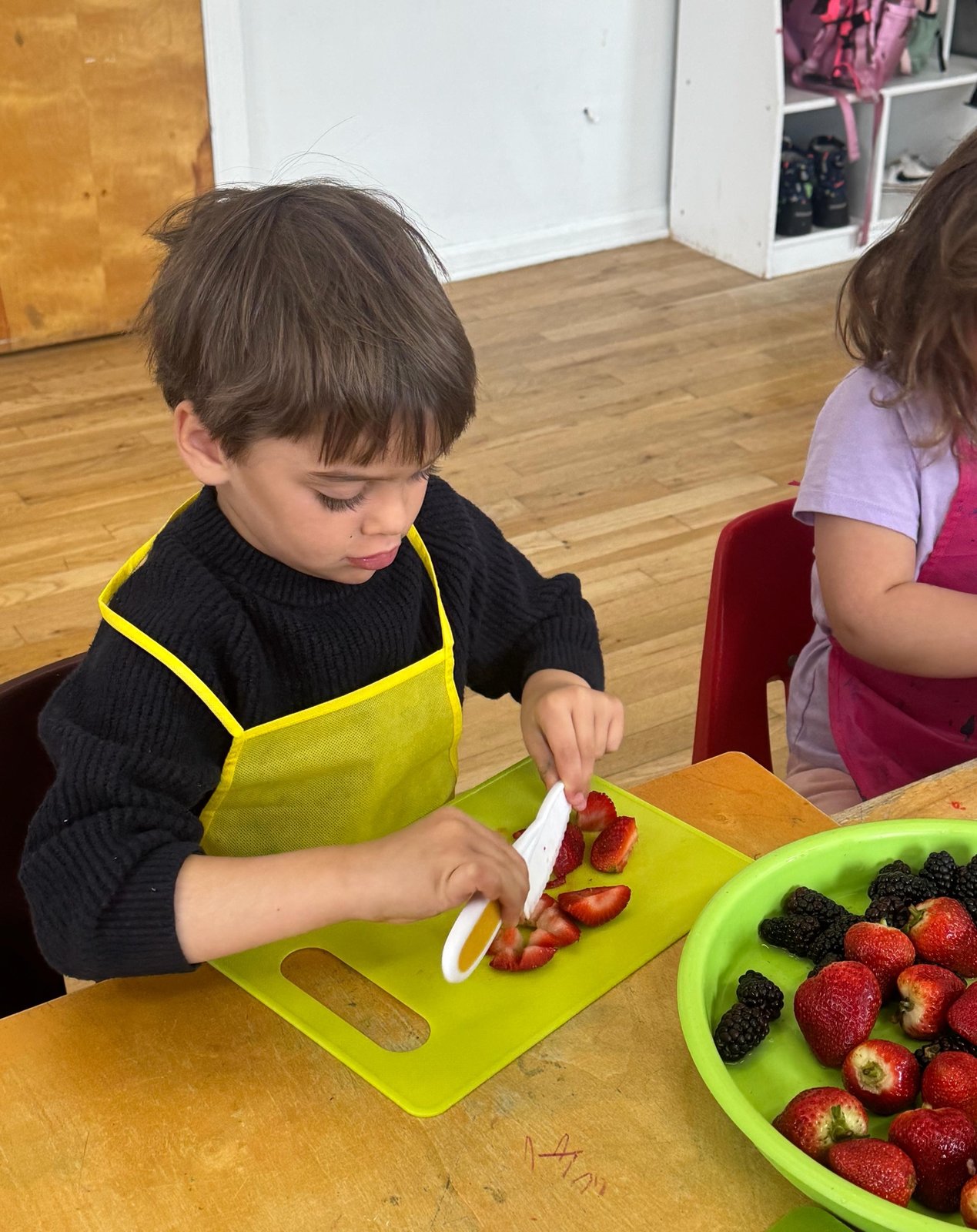 A child slicing strawberries during practical life work