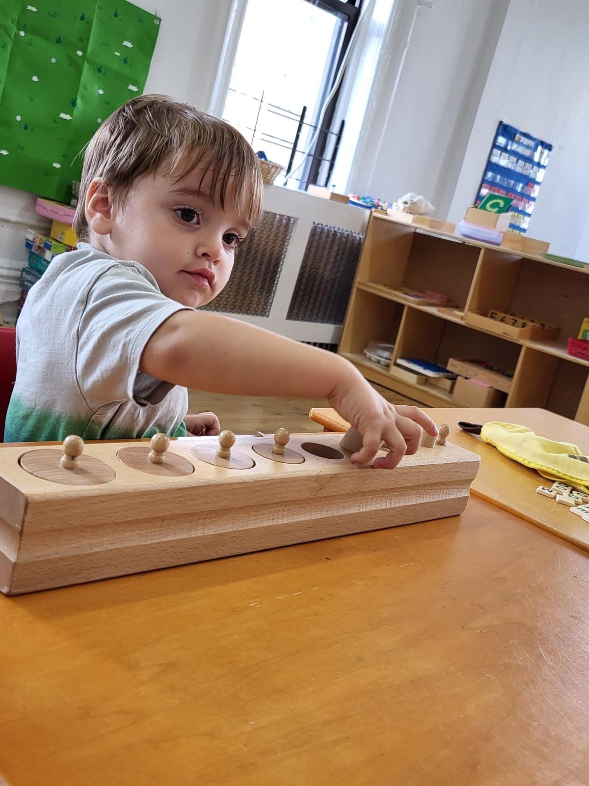 A child working with the knobbed cylinders, a Montessori sensorial material
