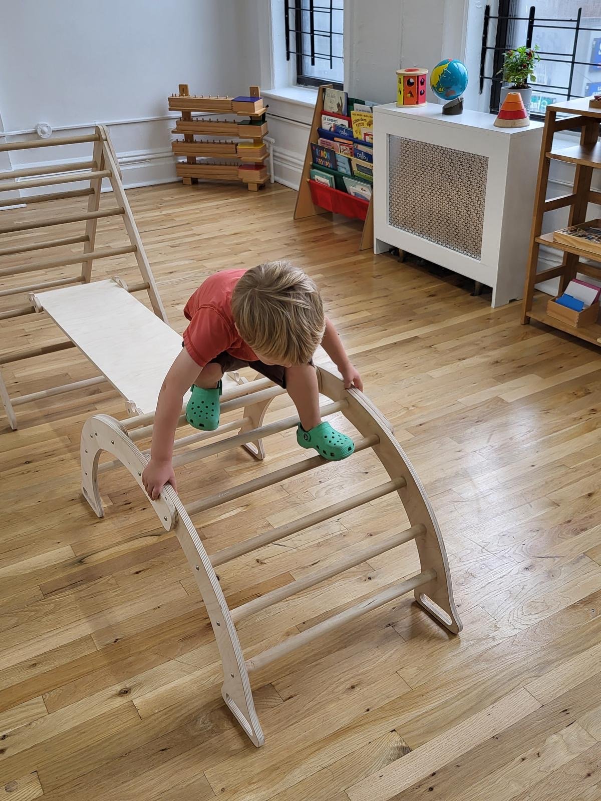 A child climbing the wooden arch during movement time
